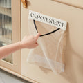 Hand pulling a plastic bag from a beige wall-mounted mesh storage bag organizer labeled CONVENIENT, hung on a cream kitchen cabinet door