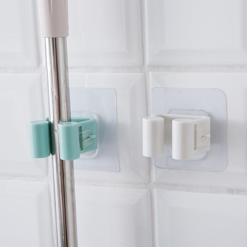 Two wall-mounted holders, one gripping a cleaning-tool handle.