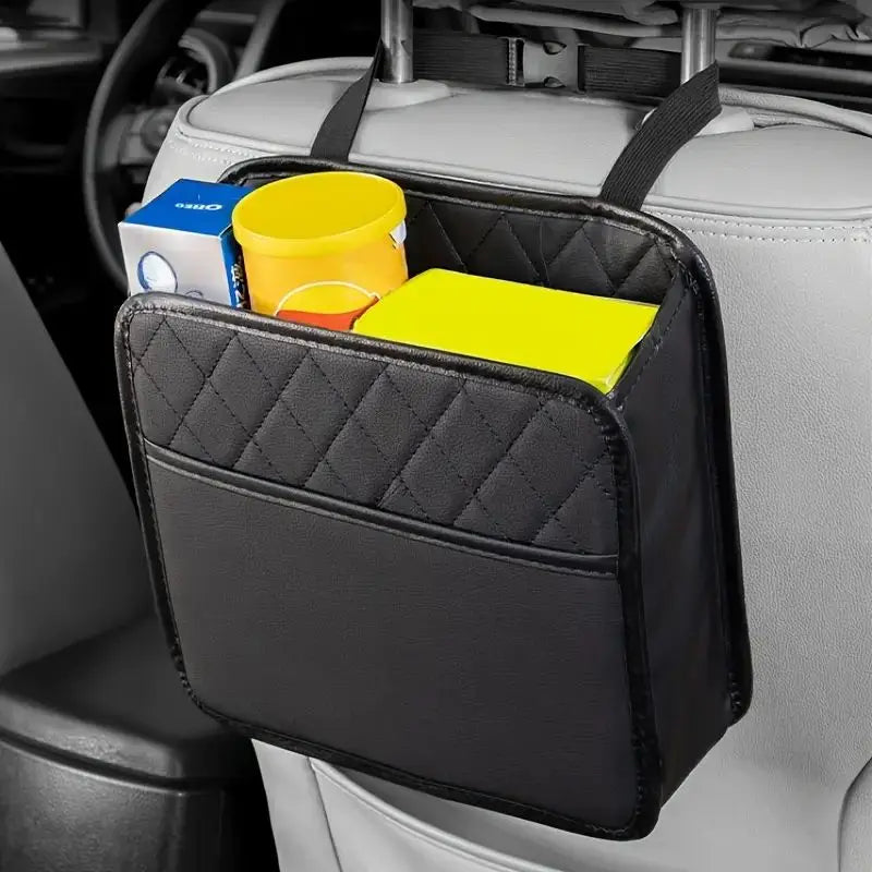 Black car seat back organizer holding snacks, a cup, and a book behind the passenger seat in a gray car interior