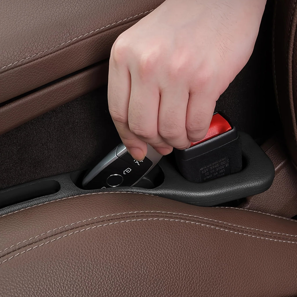 Hand retrieving a car key fob from a black car seat gap filler organizer storage groove in a brown leather vehicle interior
