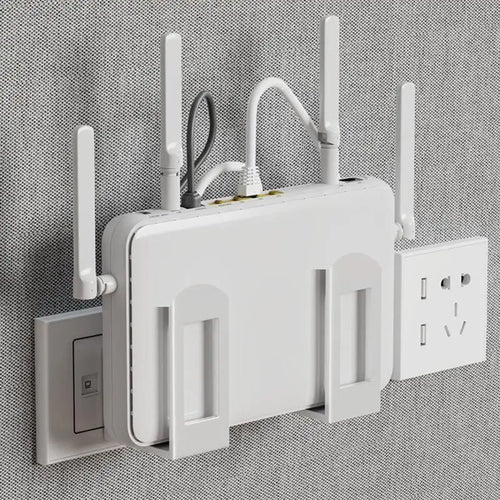 White wall-mounted router storage bracket holding a large Wi-Fi router with antennas and cables, mounted on a gray fabric wall next to a power outlet