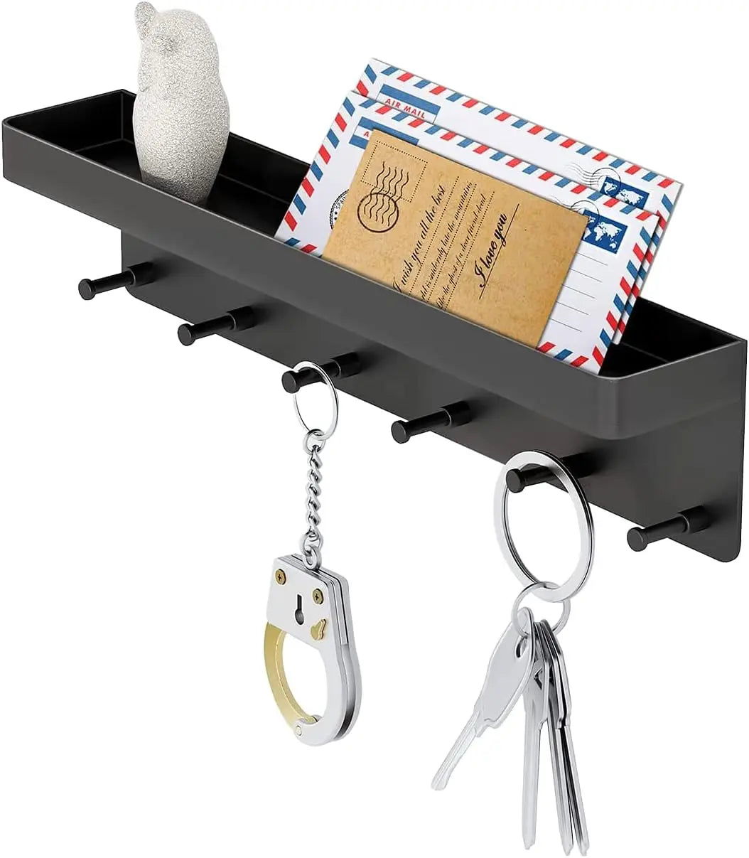 Black metal wall-mounted key holder with mail organizer shown from a front angle, top shelf holding envelopes and an owl figurine, with a handcuff keychain and house keys hanging from the 6 hooks